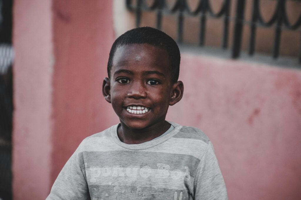A cheerful young boy smiling in an urban neighborhood setting in Cuba.